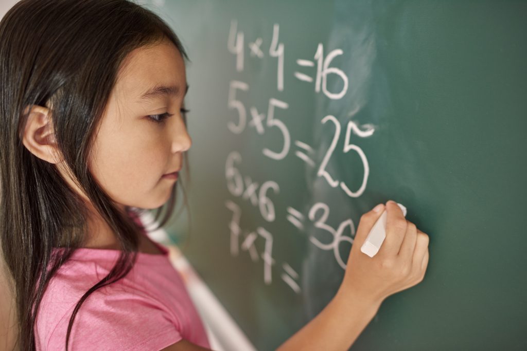 female student writing on the chalkboard as part of assignment in h2 math tuition in Singapore