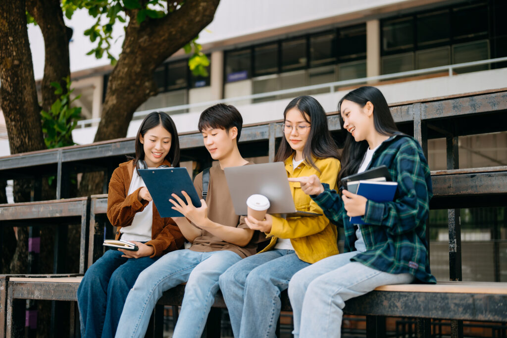 Asian Students are getting Hwa Chong math tuition in the campus park. Young people are spending time together. Reading book