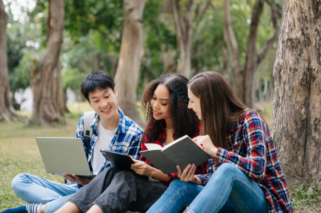 Asian teens studying H2 math tuition outside under a tree