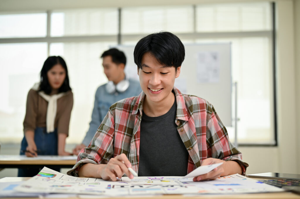 Student studying at a math tuition centre in Singapore while other teens look at him