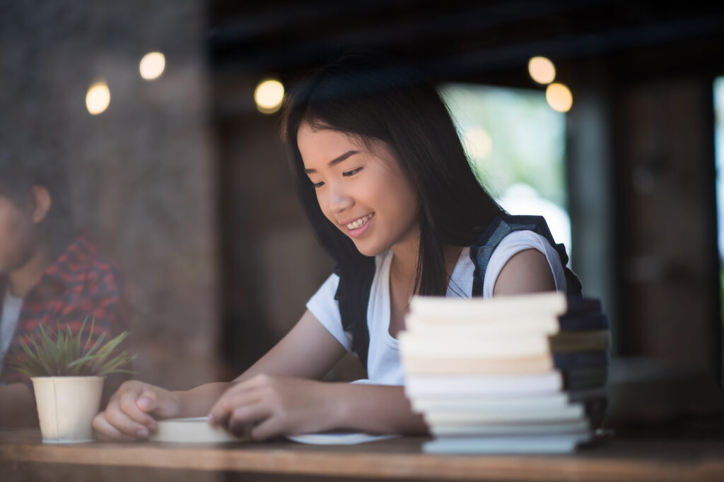 Young teen studying math tuition with piles of books beside her