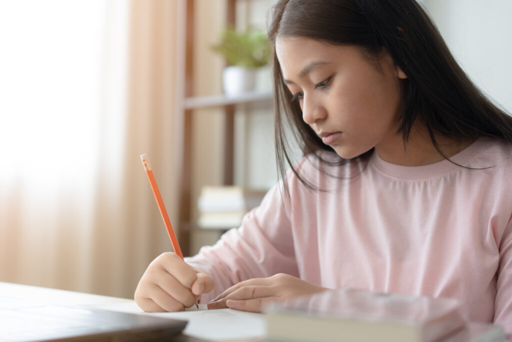 Young Asian student completing focused revision at her study desk as part of her H2 Math exam preparation.