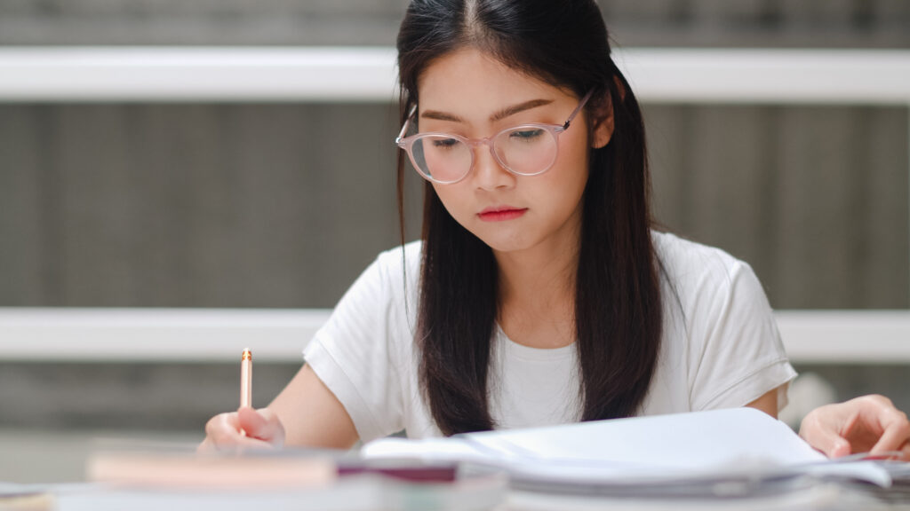 Student studying and writing in a notebook during a mathematics revision session.