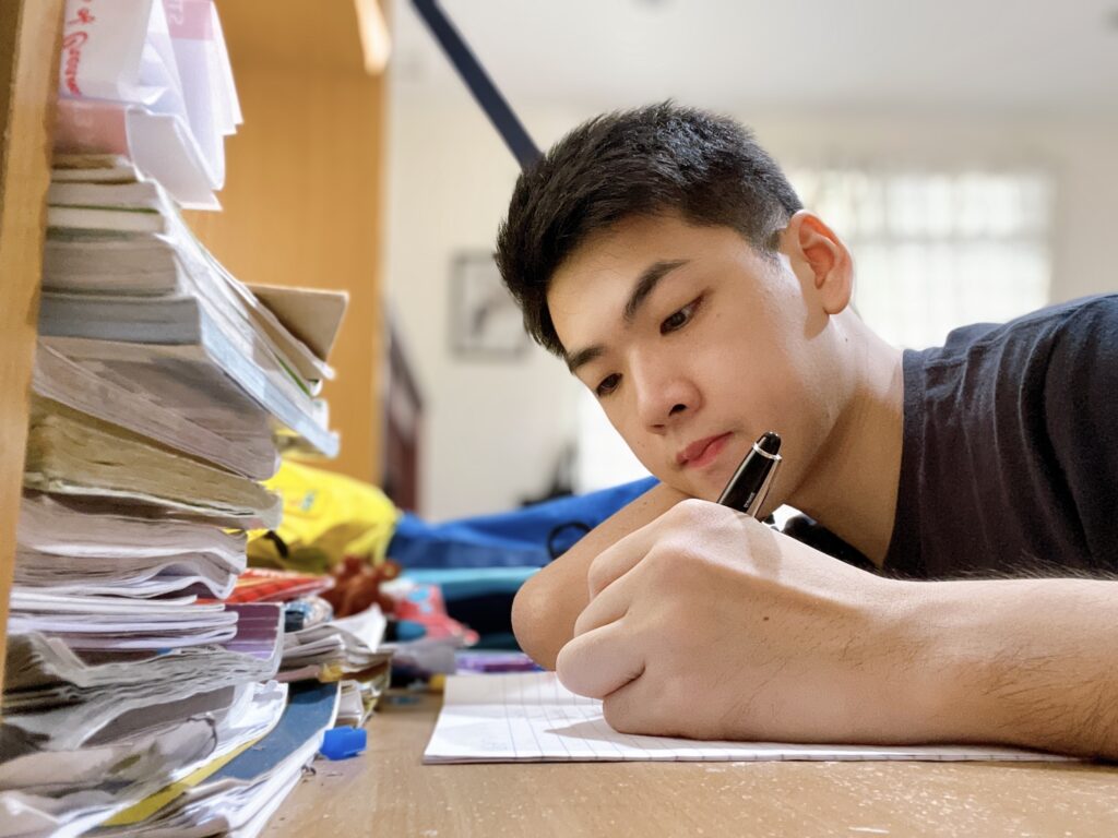 JC student completing H2 Math practice at a study desk while preparing for Paper 1 and Paper 2 examinations.